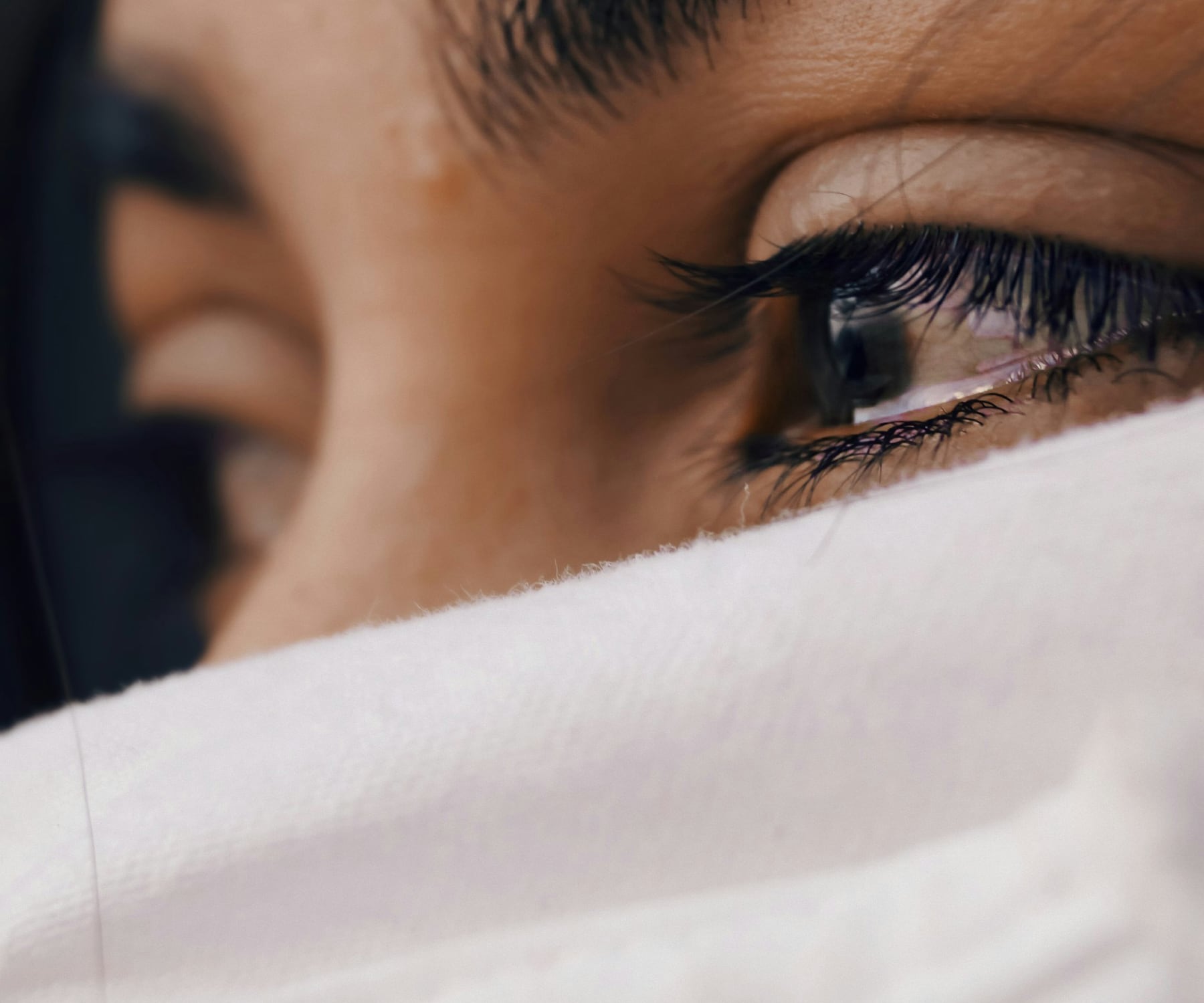 A close view of a person's eye above a white cloth held to the face
